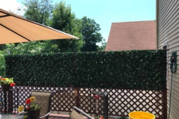 reviewer pic of faux ivy on top part of fence for some privacy in a backyard