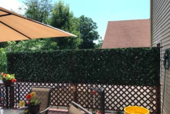 reviewer pic of faux ivy on top part of fence for some privacy in a backyard