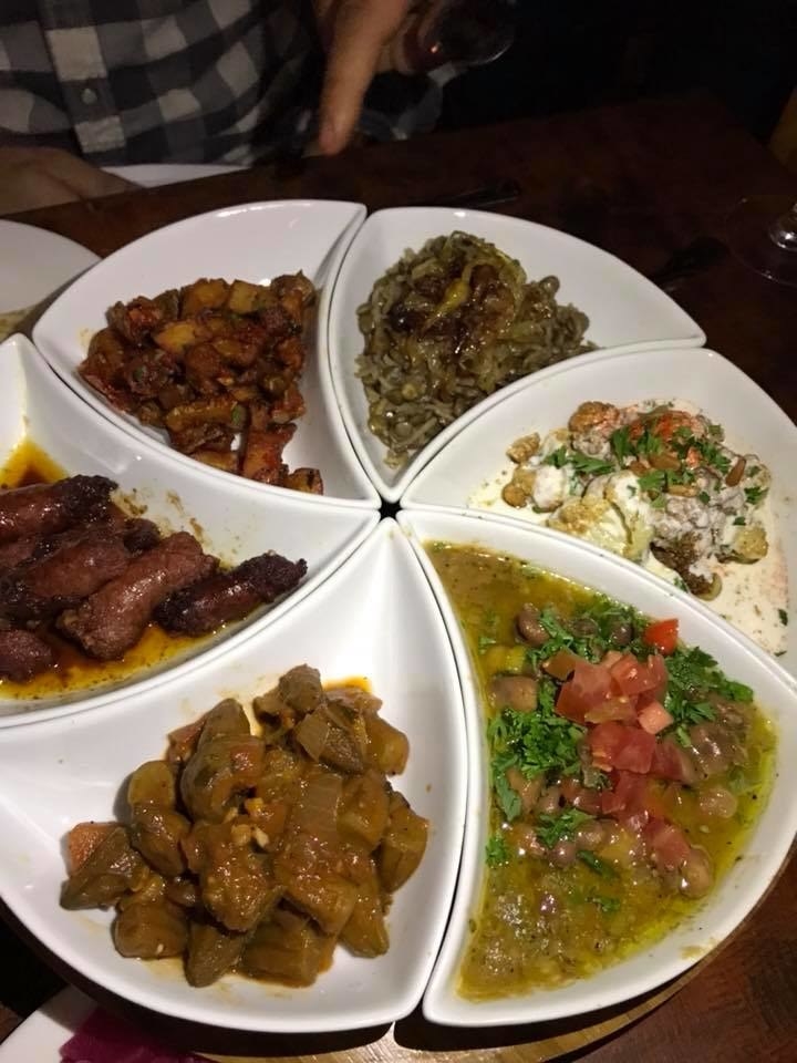 This perfectly shareable mezze platter features Mujadara (rice, lentils & caramelized onions), Arnabeet Bi Tarator (flash-fried cauliflower with parsley tahini sauce topped with toasted pine nuts), Foul Medamas (a blend of fava beans, garlic, lemon juice, cumin & extra virgin olive oil), Bemieh Bzeit (fresh baby okra sautéed in extra virgin olive oil with garlic & cilantro), Soujouk (house-made spicy beef sausages sautéed with fresh tomatoes & extra virgin olive oil), and Batata Harra (sauteed spicy potato cubes with cilantro, garlic & red pepper flakes)