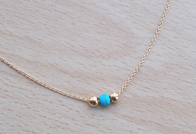 A minimalistic gold and turquoise beaded necklace.