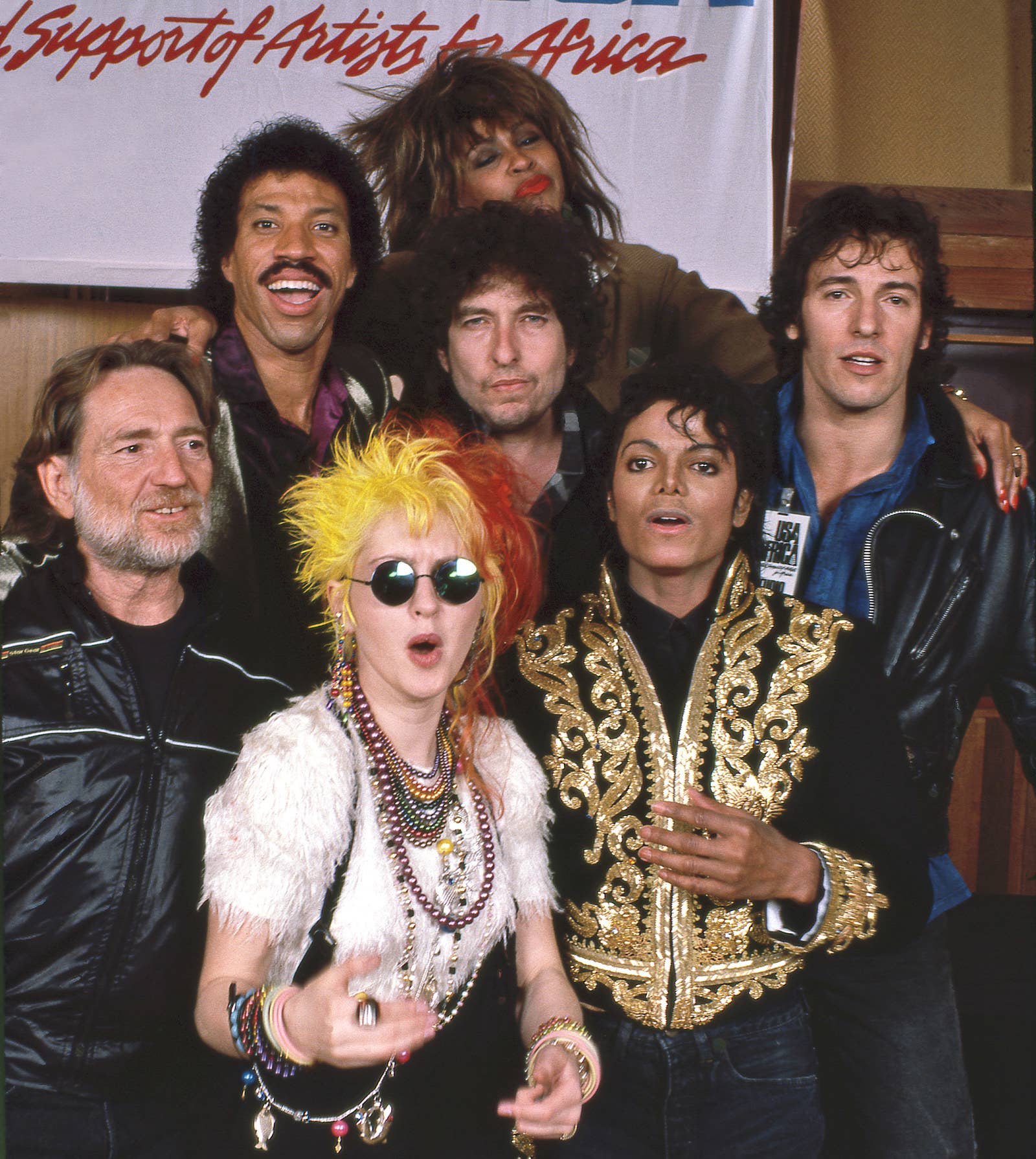 Em sentido horário, da esquerda para cima: Willie Nelson, Lionel Richie, Tina Turner, Bruce Springsteen, Bob Dylan, Michael Jackson e Cyndi Lauper em Los Angeles, janeiro de 1985.