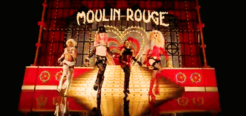A GIF from the &quot;Lady Marmalade&quot; music video of Lil&#x27; Kim, Pink, Mya, and Christina Aguilera walking from the Moulin Rogue stage
