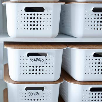 Stacked white storage bins labeled for scarves and socks in an organized closet space