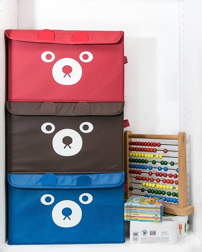 red, brown, and blue bins with bear faces stacked on top of each other