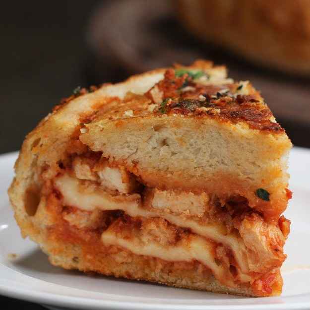 6 servingsINGREDIENTS115 g (1 cup) breadcrumb1/2 teaspoon fresh parsley, chopped1/2 teaspoon garlic powder1/2 teaspoon onion powder1/4 teaspoon dried oregano1/2 teaspoon salt1/4 teaspoon pepper125 g (1 cup) flour3 egg, beaten2 boneless, skinless chicken breast, thinly sliced oil, for frying1 bread boule260 g (1 cup) marinara sauce225 g (8 oz) mozzarella cheese50 g (1/2 cup) shredded parmesan cheese3 tablespoons butter, melted3 cloves garlic, minced1 tablespoon fresh parsley, chopped1 tablespoon parmesan cheese, grated fresh basil, for servingPREPARATION1. Preheat oven to 350°F (180ËC).2. In a medium bowl, combine bread crumbs, parsley garlic powder, onion powder, oregano, salt, and pepper to bread crumbs.3. Place flour and eggs in two other medium bowls.4. Roll the chicken breast in the flour, dusting off any excess. Dip the chicken into the egg, then place into the breadcrumbs, coating it completely.5. Heat the oil in a skillet over medium-high heat.6. Once the oil begins to shimmer, fry the breaded chicken strips until both sides are golden brown.7. Remove from heat and drain on a paper towel.8. Slice the cooked chicken breast into ½-inch (1 cm) thick strips.9. Slice the top of the bread boule off and scoop out the insides. Save the top of the boule.10. Spoon and spread some of the marinara sauce on the bottom of the boule, then layer on mozzarella, Parmesan cheese, chicken strips, marinara, remaining mozzarella, Parmesan, chicken strips, marinara, and remaining Parmesan.11. Place the cap of the bread boule on top.12. Wrap the bread bowl in foil, then weigh it down with a heavy object for 30 minutes.13. In a small bowl, mix together butter, garlic, parsley, and Parmesan cheese.14. Remove the foil from the bread bowl and brush the garlic butter mixture evenly over it.15. Bake for 30 minutes.16. Cool for 10 minutes and slice.17. Garnish with basil, if desired.18. Enjoy!Inspired by:https://tasty.co/recipe/chicken-parmesan-stuffed-garlic-bread