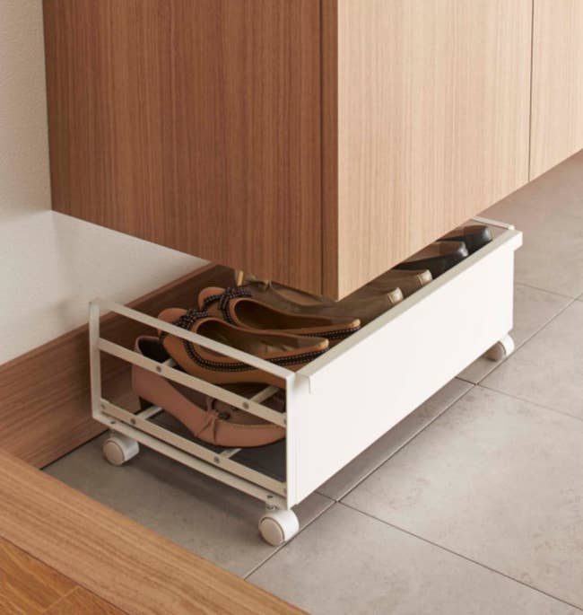 Rolling footwear  retention  rack nether  a woody  cabinet, showcasing organized footwear successful  a minimalist, space-saving solution