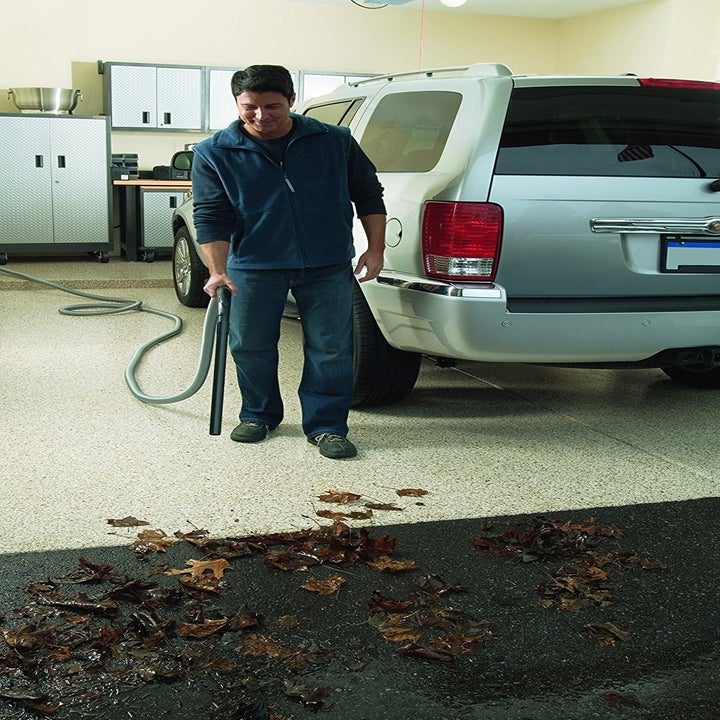 a model using the shop vac to remove leaves from his garage