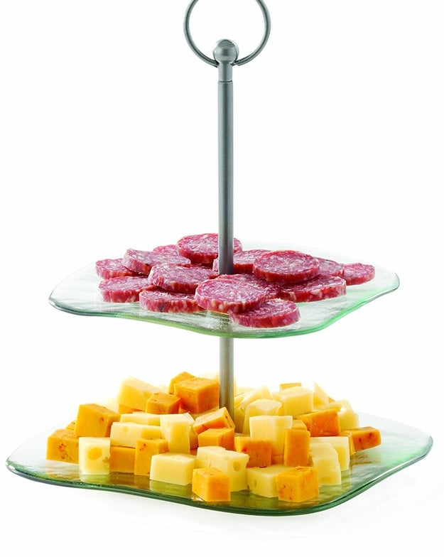 A two-tiered serving tray with a steel rod for easy handling and is made from recycled glass.