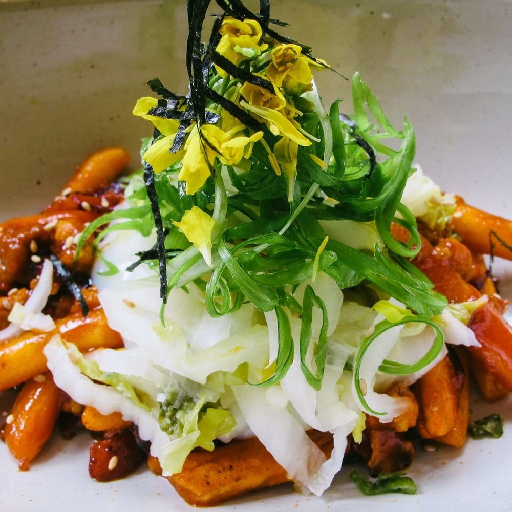 In addition to ramen, Mokbar has delicious, shareable snacks like Tteokboki and Mok Wings. The Tteokboki features crispy rice cakes sauteed in brown butter with bacon and minced pork in spicy gochujang sauce. The dish is topped with pickled white kimchi, cilantro, and nori.