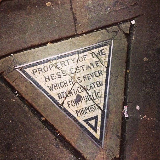 Themosaic reads, "PROPERTY OF THE HESS ESTATE WHICH HAS NEVER BEEN DEDICATED FOR PUBLIC PURPOSES." Despite the city urging them to donate the tiny land, they refused. It's still there today.
