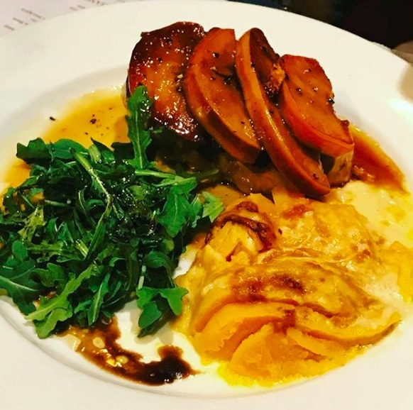 A tender, juicy piece of pork chop - topped with caramelized onion and grilled apple slices - is paired with arugula salad lightly tossed in vinaigrette and butternut squash gratin that just melts in your mouth. An unforgettable dish!