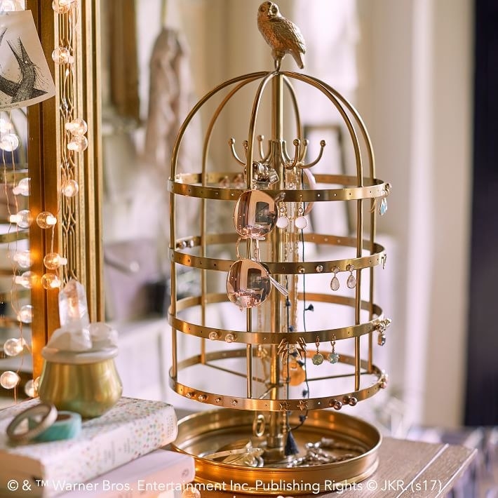 The jewelry display in the shape of a round-top bird cage with a little owl figure on top