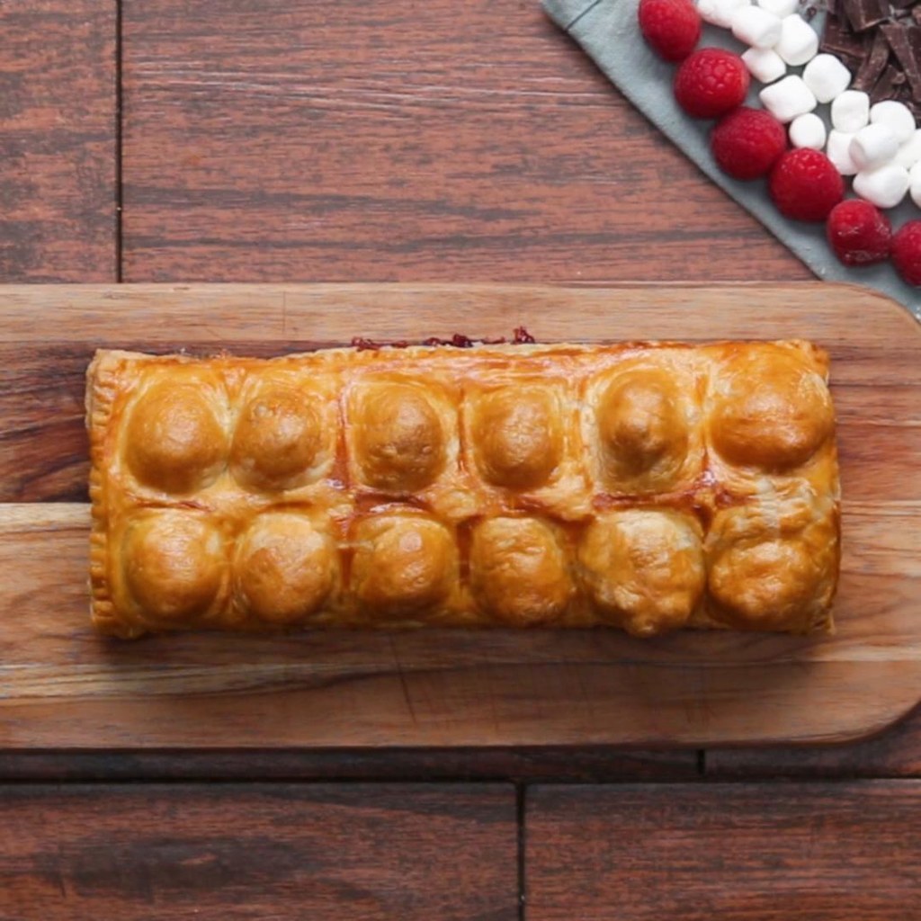 12 servingsINGREDIENTS1 package frozen puff pastry, thawed55 g (1/4 cup) chocolate hazelnut spread1/2 banana, sliced80 g (1/4 cup) raspberry jam1/2 chocolate bar, broken into 4 squares45 g (1/4 cup) chocolate chip12 mini marshmallow1/2 graham cracker, broken into 4 squares egg washPREPARATION1. Preheat oven to 400ËF (200ËC).2. Lay a sheet of puff pastry dough over the ice cube tray and carefully press into the dough forming it to the ice tray.3. Place a spoonful of chocolate hazelnut spread and a slice of banana in the first four cube divots.4. Place a spoonful of raspberry jam and a piece of chocolate in the middle four cube divots.5. Place the chocolate chips, marshmallows, and graham cracker into the last 4 cube divots.6. Place the other sheet of puff pastry over the ice cube tray and use a rolling pin to seal it. Chill for at least 10 minutes.7. On a parchment paper-lined baking sheet, invert the ice cube tray releasing the puff pastry pockets.8. Using a knife cut any excess dough from the sides.9. Using a fork, press into the the edges of the pastry and seal.10. Brush the pastry with egg wash and bake for 30 minutes.11. Enjoy!Inspired by:https://www.facebook.com/ciaopeoplecookist/videos/238395449971860/?permPage=1