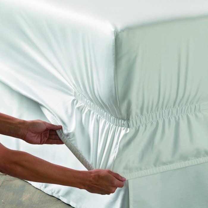 person pulling sheets down over corner, showing the deep pockets