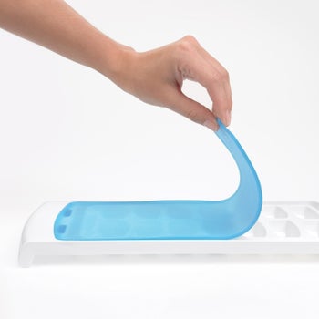 hand peeling up thin silicone lid on ice cube tray