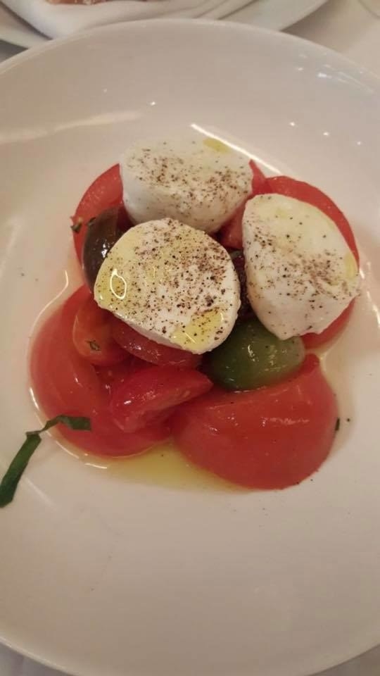 Start the meal with fresh burrata paired with juicy heirloom tomatoes and basil. The melt-in-your-mouth burrata is drizzled with extra virgin olive oil and ground black pepper, complemented by sweet, succulent tomatoes.