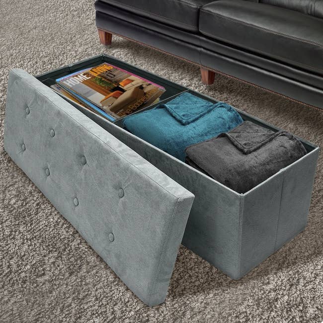 long gray storage bench with the top off revealing blankets and magazines