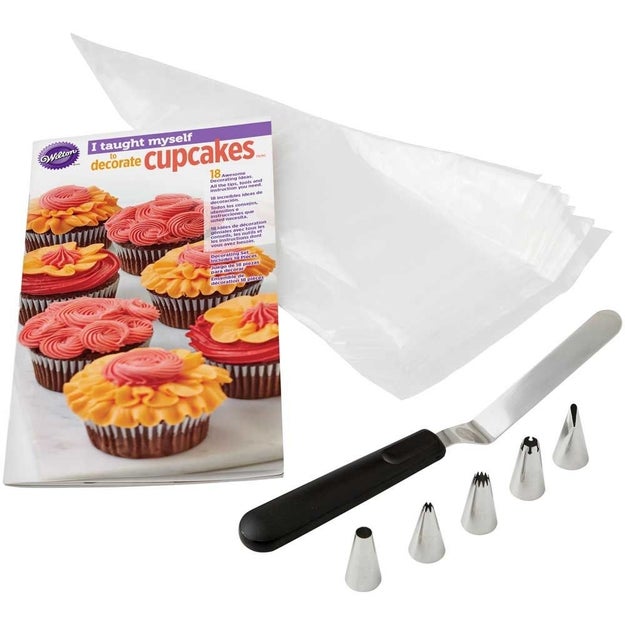 A cupcake decorating set with a step-by-step guide book, piping bags, and an assortment of icing tips.