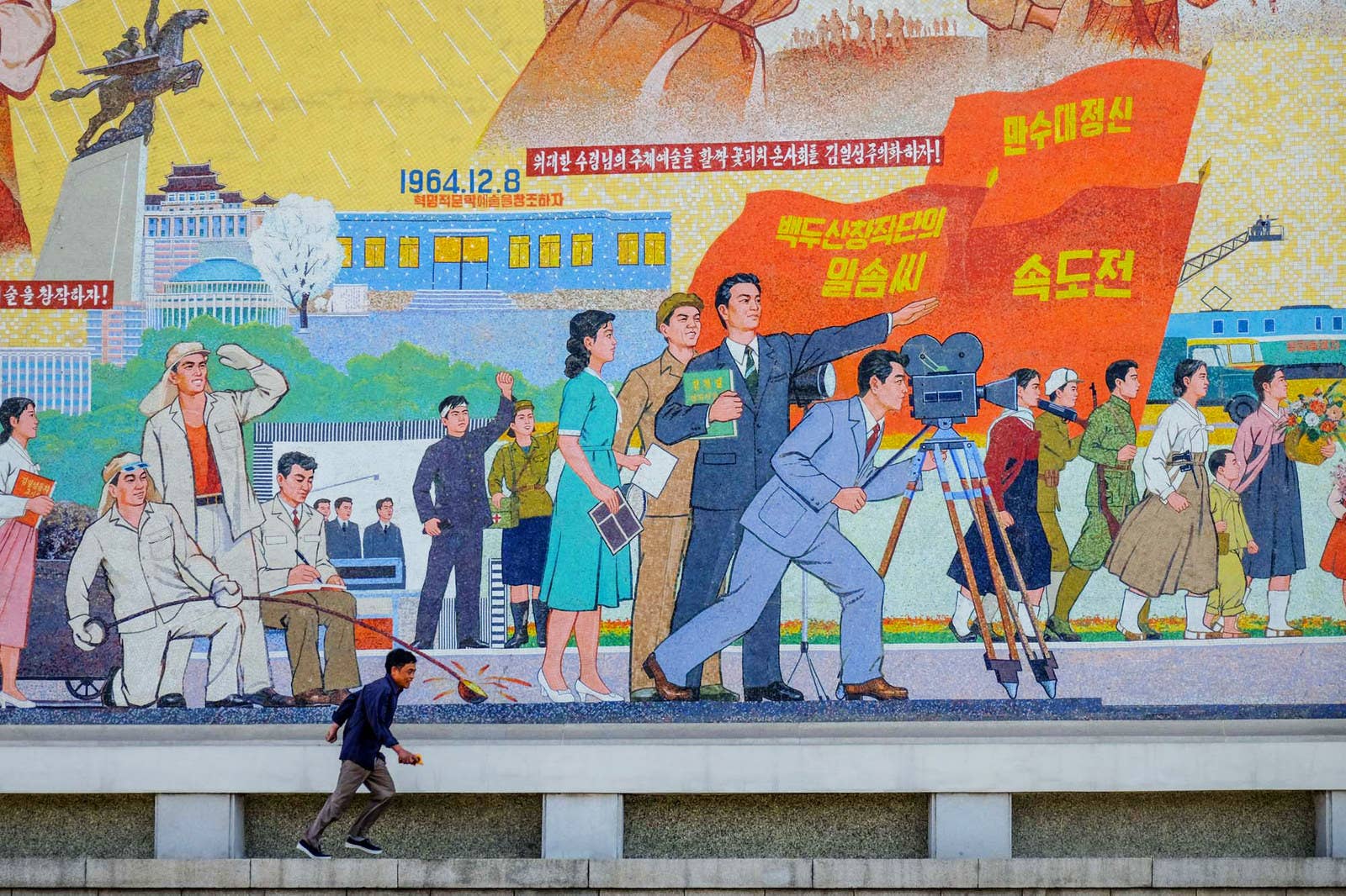 A man runs past monumental mosaics at Pyongyang film studios.