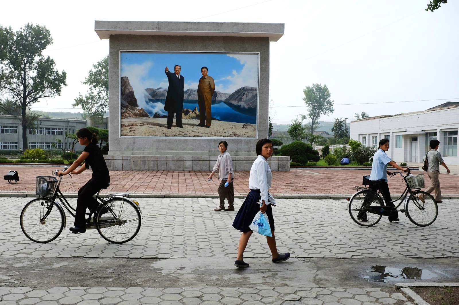 People in provincial North Korea pass before a mural of the leaders standing upon the North Korean "sacred mountain" of Mount Paektu.
