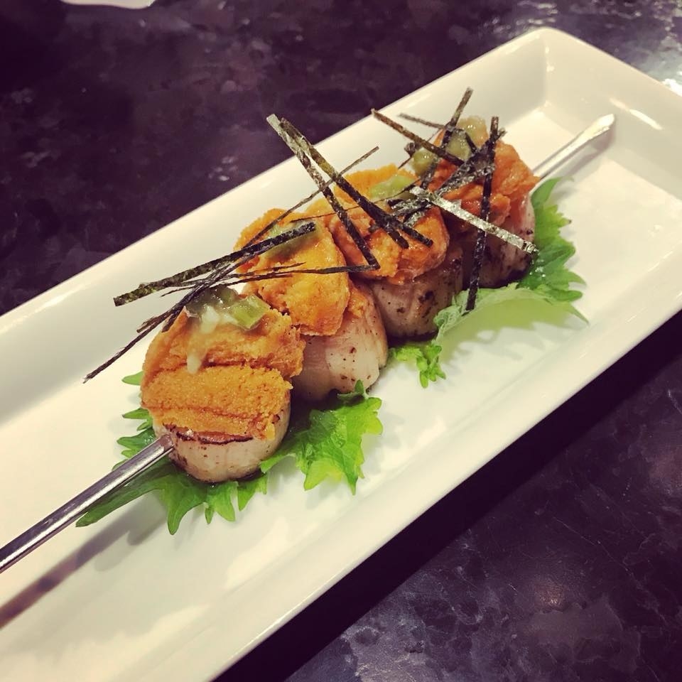 Served in a skewer, the soy-marinated, plump scallops are topped with fresh sea urchin. The uni is garnished with slightly spicy jalapeño bits and strips of seaweed, all over minty shisho leaf.