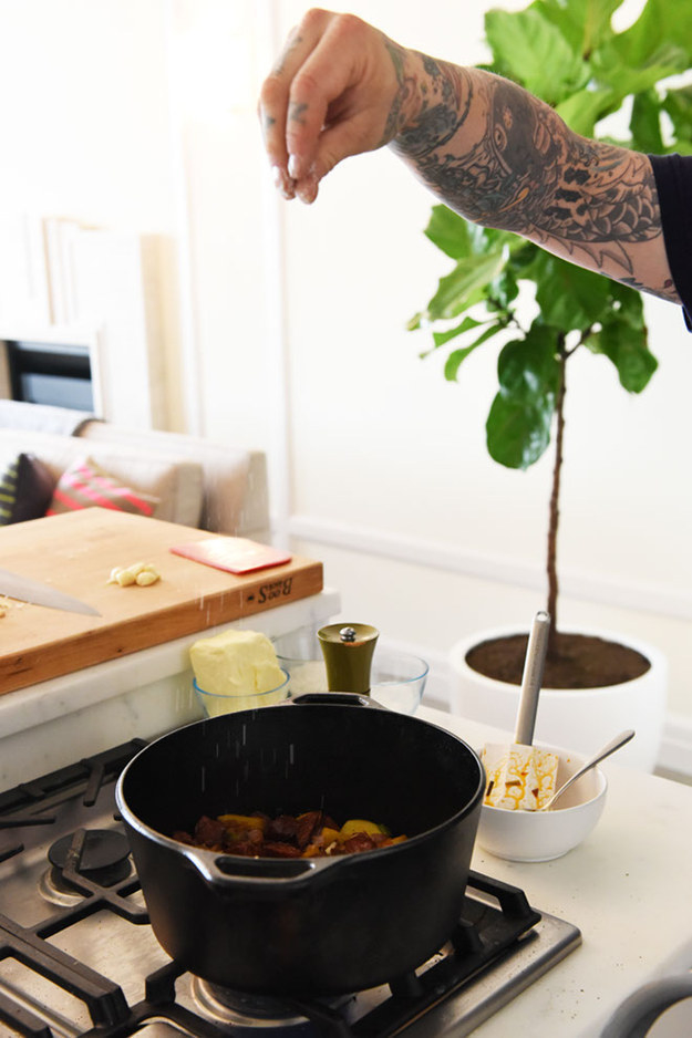 A hand sprinkling salt into a dutch oven from about two feet up