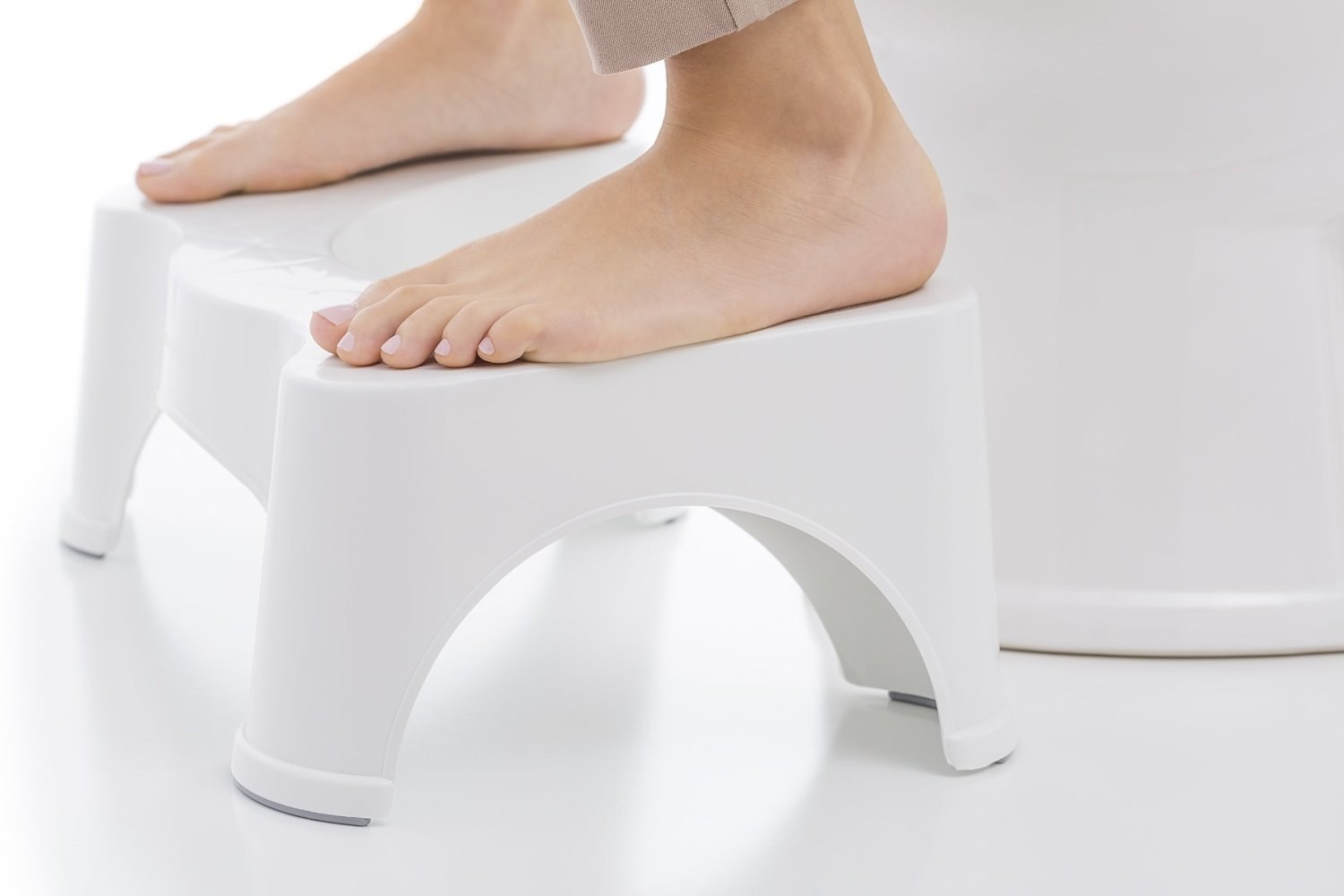 Feet elevated with stool in front of toilet 