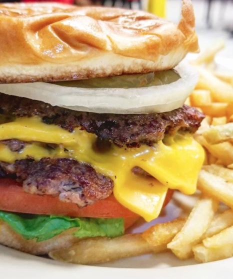 Close-up of a very thick cheeseburger with onions, lettuce, and lettuce