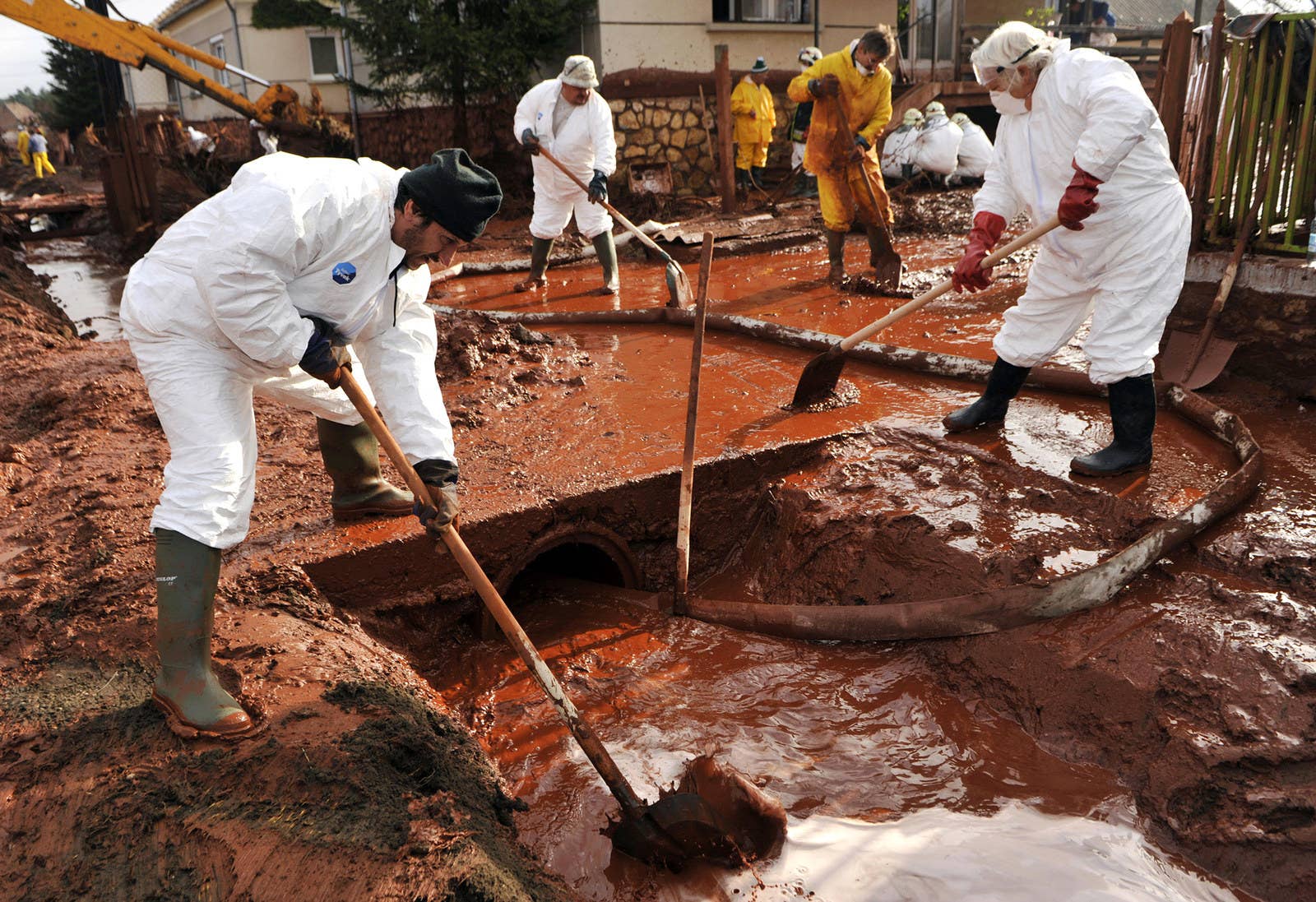 ハンガリーのコロンタールでは、地域住民が防護服を着て有毒の泥で汚染された道を掃除した。(2010年10月7日)