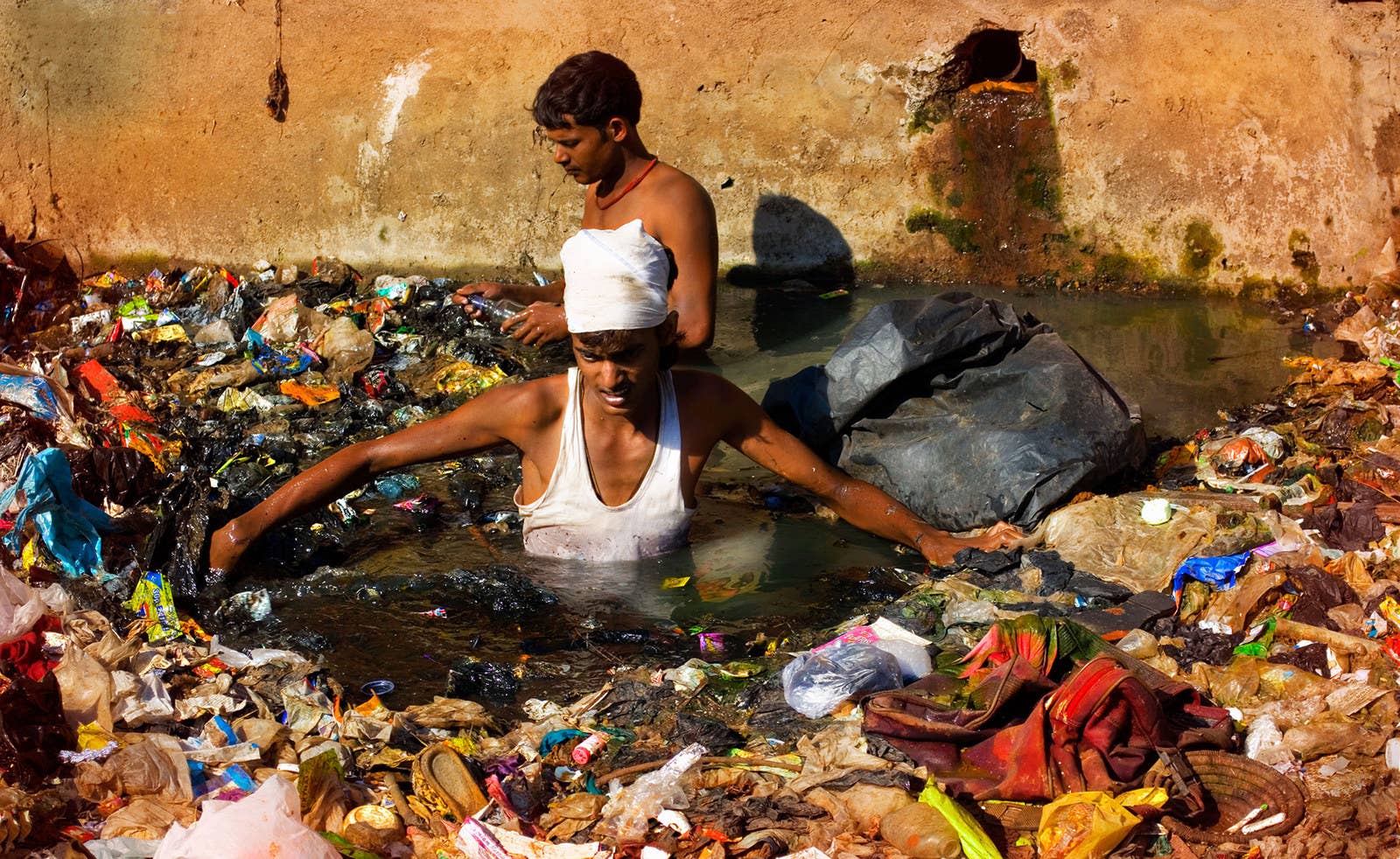 インド・ムンバイで、汚染された川に浮かぶゴミを漁る男性。この川は市民から下水溝のように扱われており、生ゴミ、産業廃棄物、その他様々なゴミが見境なく捨てられている。(2013年1月24日)