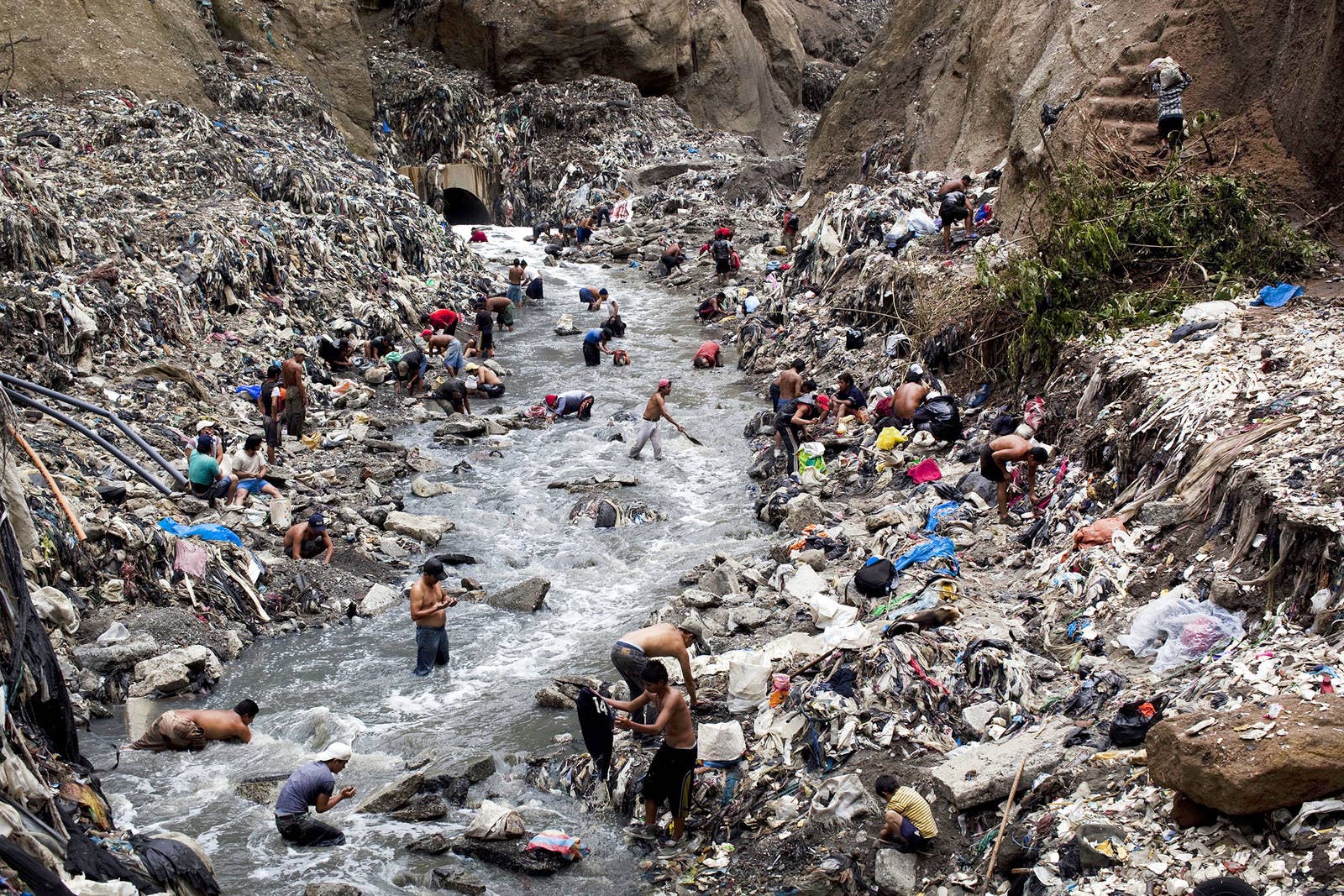 グアテマラシティ最大のゴミ置場は宝の山として知られている。人々は鉄くずを見つけるため汚染された水の中を探る。(2011年10月19日)