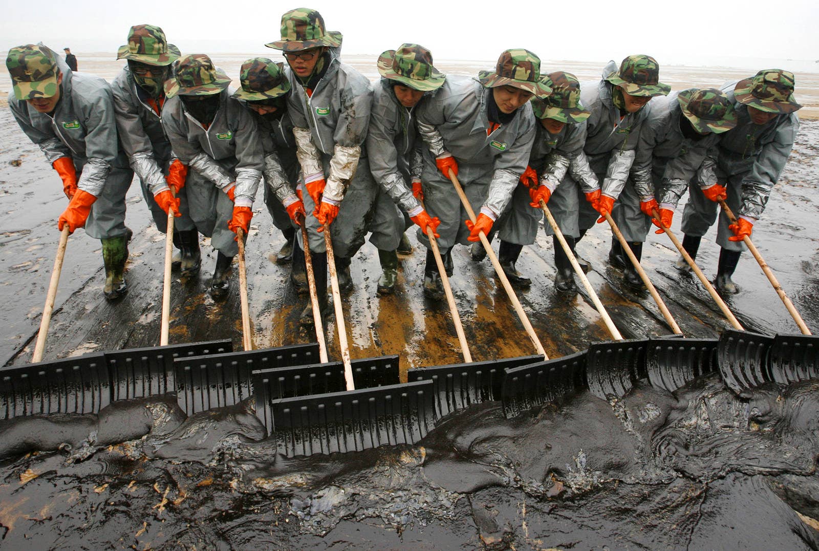 韓国のオイルタンカーの事故後、万里浦海水浴場に漂着する原油を取り除くために働く兵士たち。(2007年12月10日)