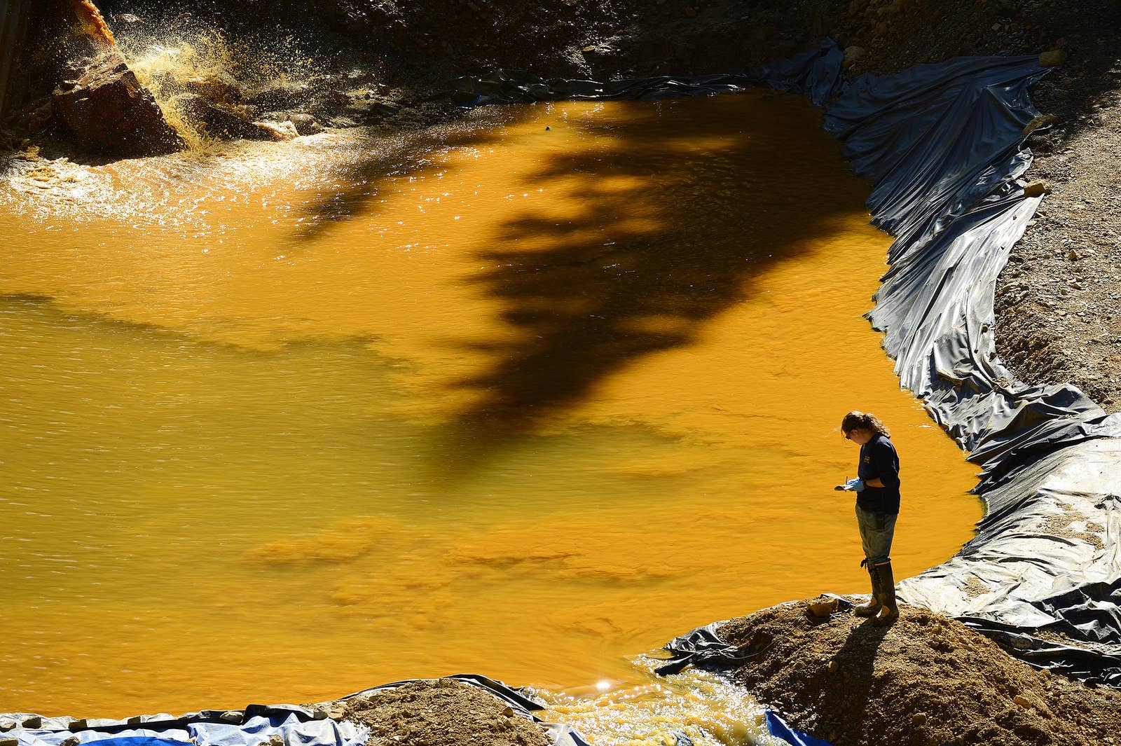 コロラド州ゴールドキング鉱山のすそにある貯水池の脇を歩くウェストンソリューションズの社員。2015年8月5日に汚染水の流出事故が起きたこの鉱山では、米環境保護庁や同社、沿岸警備隊などが4つの貯水池の水の浄化と、5つめの池の建設建設を支援している。(2015年8月13日)