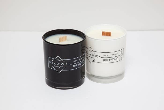 a black candle next to a white minimalist design next to a white candle with black design, both with thick wood wicks