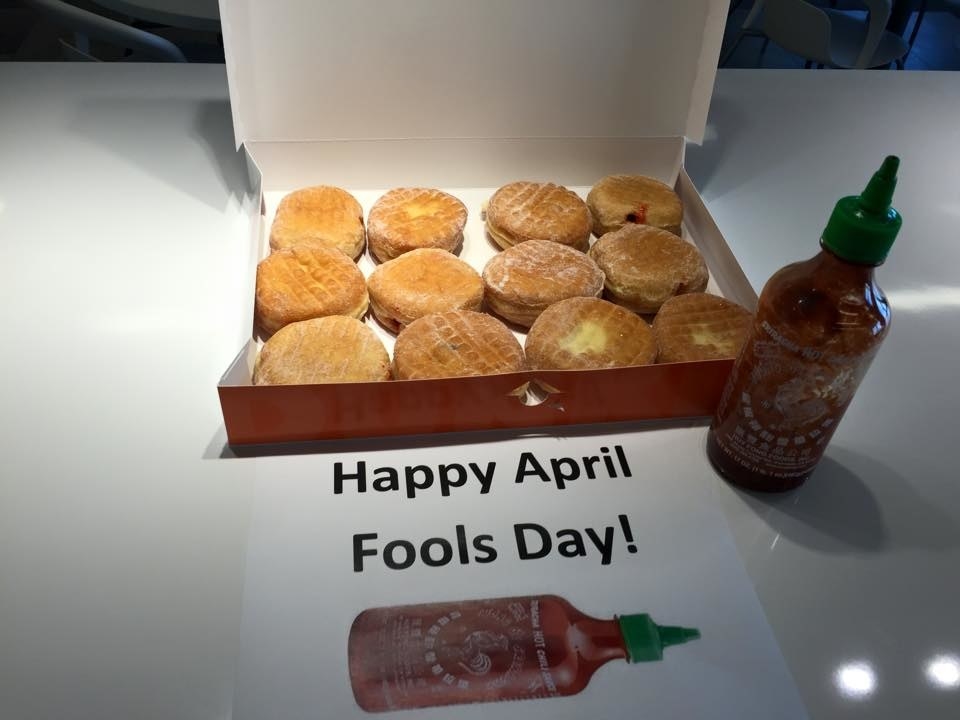 Box of round pastries next to a hot sauce bottle with a label &quot;Happy April Fools Day&quot;