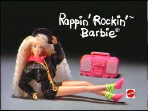 A screenshot of a Barbie doll sitting wearing a black jacket, mini-skirt, and hat, with a pink boombox in the back and the words &quot;Rappin&#x27; Rockin&#x27; Barbie&quot; written in chalk-esque font above it.