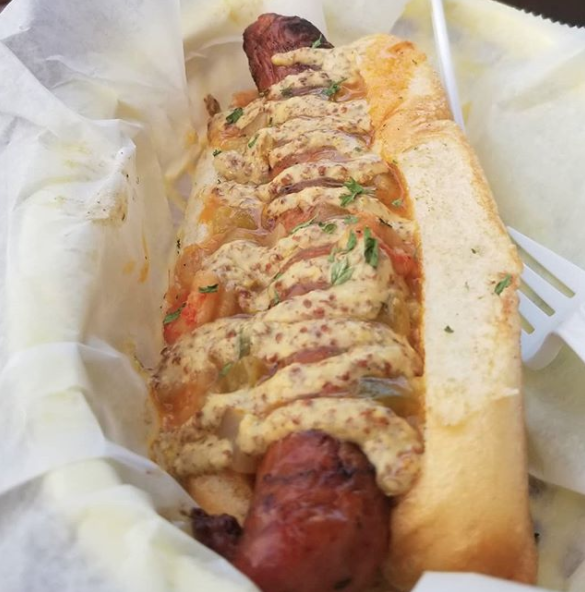 A crawfish étouffée hot dog in a bun with Creole mustard