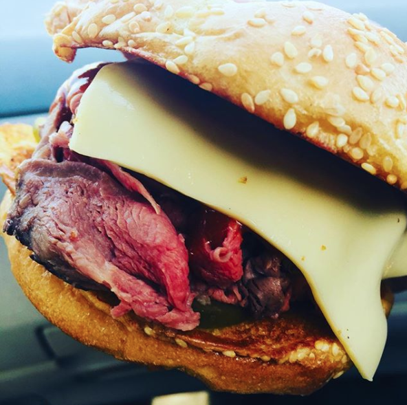 Close-up of roast beef sandwich with cheese on a seeded bun