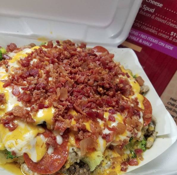 Crumbled pepperoni, cheese, and condiments on a potato