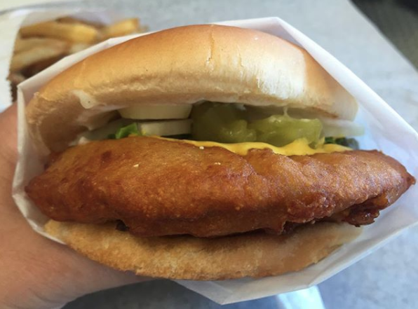 Close-up of a pork chop bun with cheese, pickles, and onion