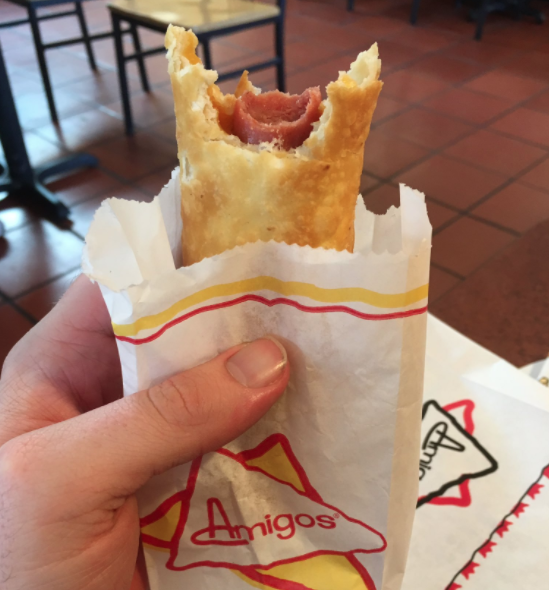 Half-eaten hot dog and cheese in a tortilla