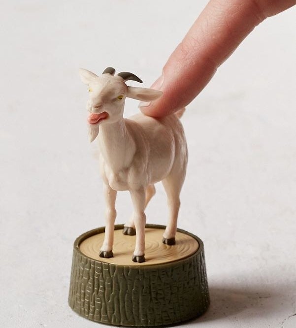 small goat figure with button on back on stump 