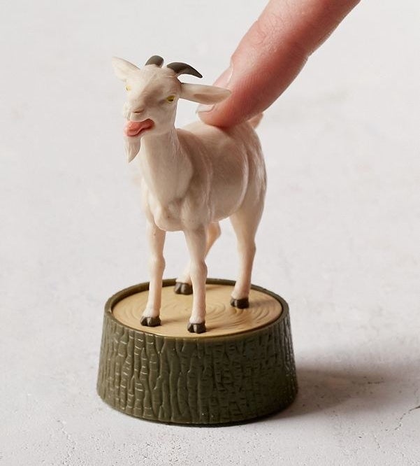 small goat figure with button on back on stump 