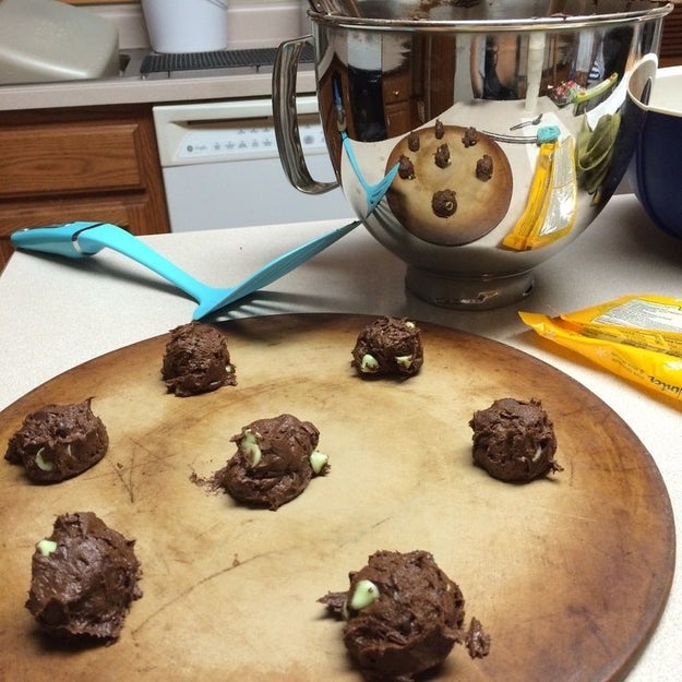 The reflection of these cookies being prepared on a board, which resembles one giant chocolate chip cookie.