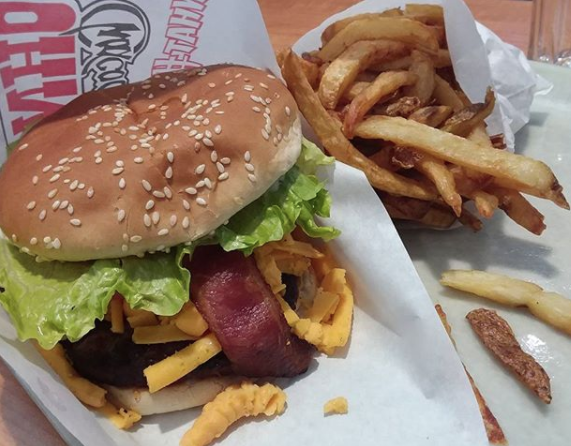 Close-up of a bacon burger on a seeded bun and fries
