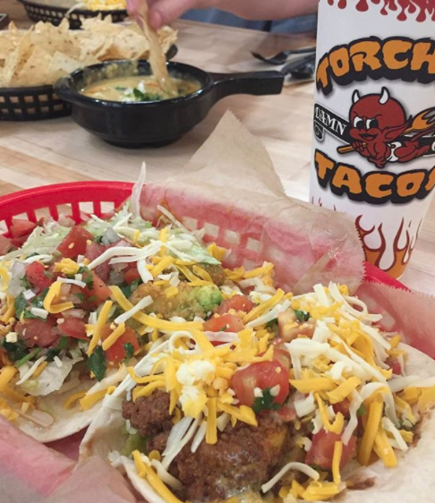 Close-up of open tacos with chicken, shredded cheese, salsa, and other condiments