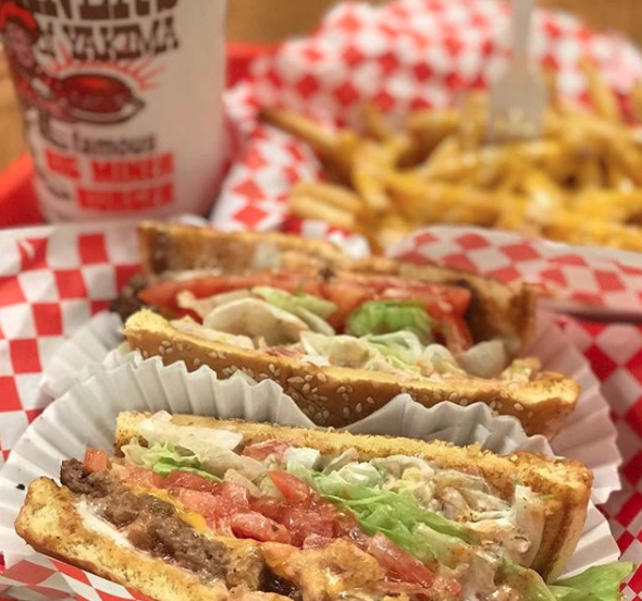 Close-up of a thick, open-faced sandwich with meat, lettuce, tomato, and condiments