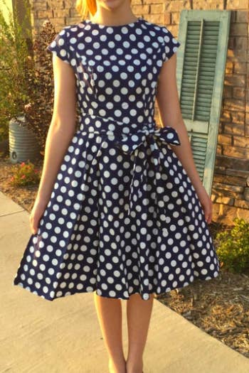A reviewer wearing the dress in blue with white polka dots