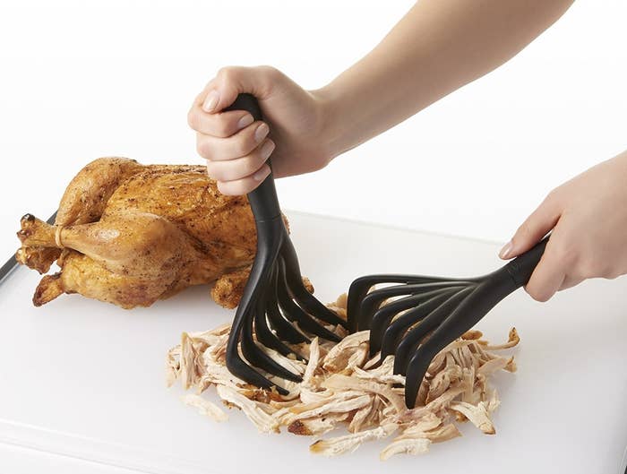 Hands shredding a rotisserie chicken with the black claws