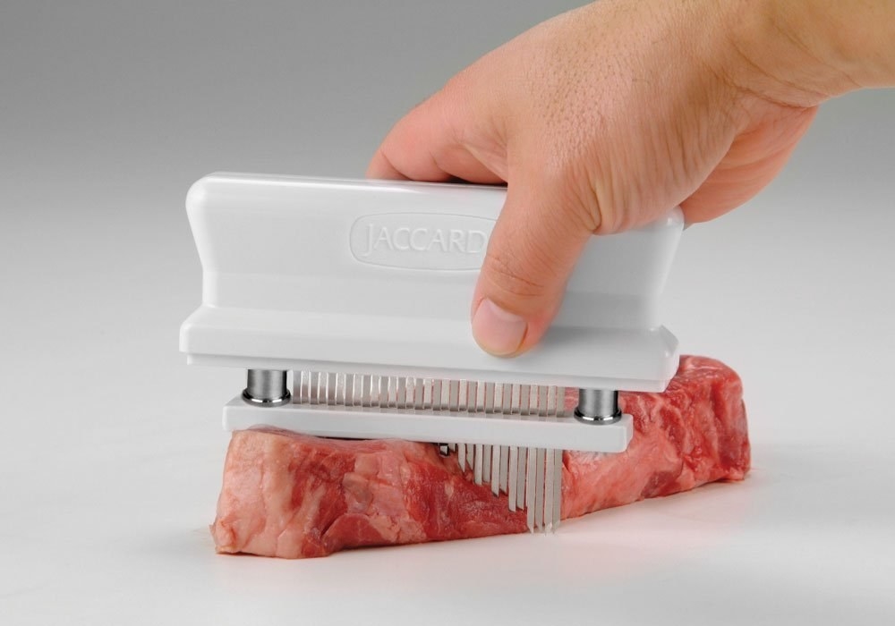 The white tenderizer with base, with rows of needles to puncture the meat